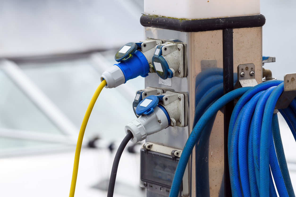 Biała turbina wiatrowa obracająca się na zielonej łące obok paneli słonecznych